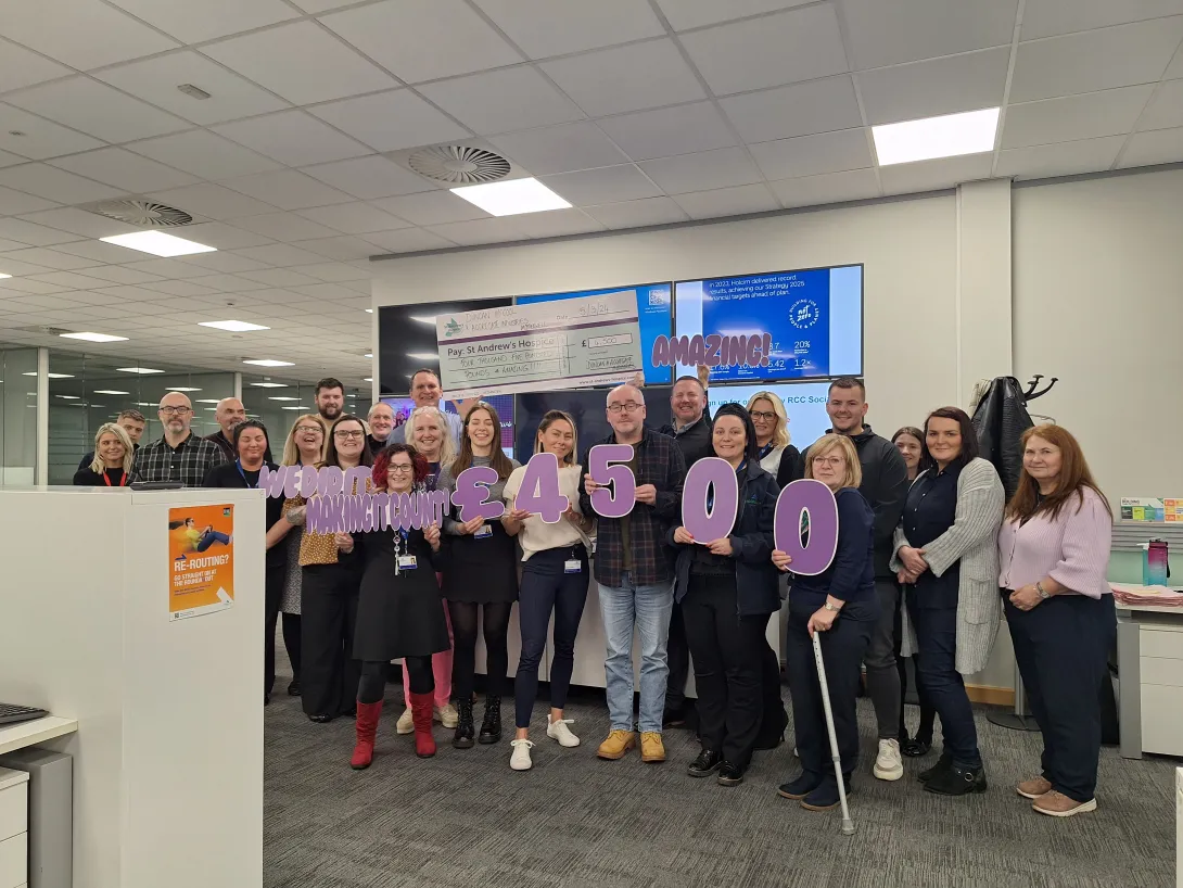 Staff at Trilogy RCC holding up £4500 banner celebrating how much they have raised for St Andrew's Hospice in Lanarkshire