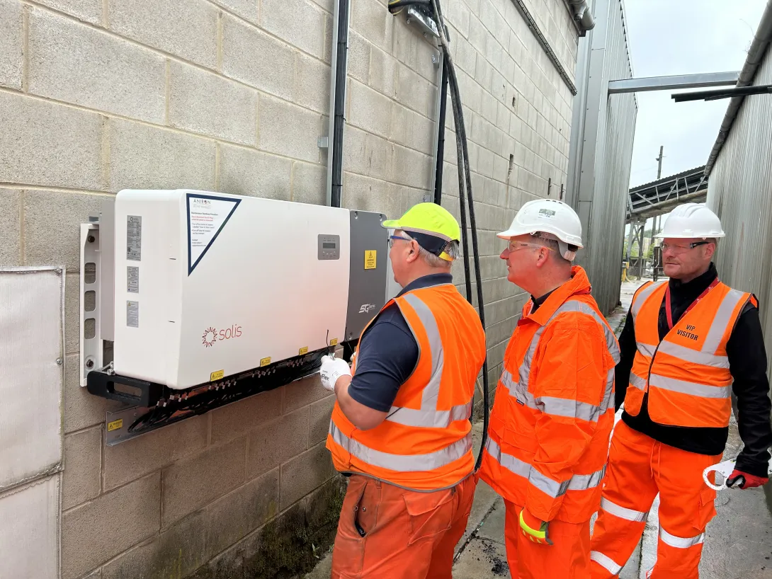 Workers survey one of the solar control panels connected to the rooftop panels at Aggregate Industries' Hulland Ward site